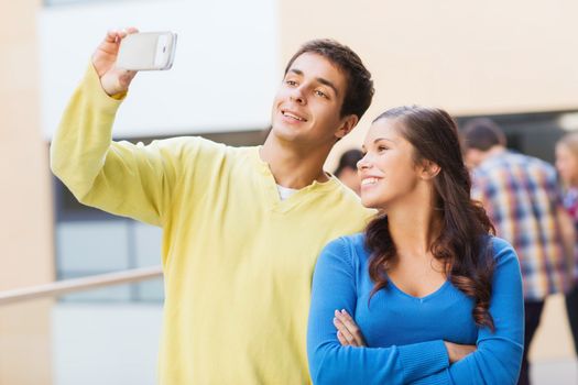 friendship, education and people concept - group of smiling students making selfie with smartphone outdoors