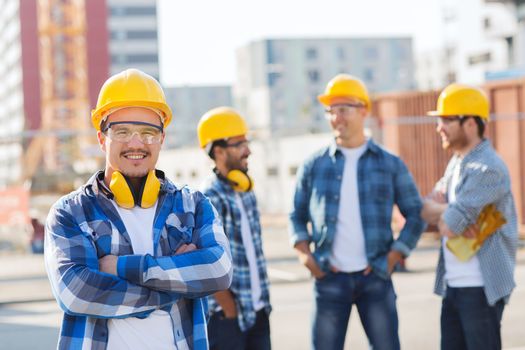 business, building, teamwork and people concept - group of smiling builders in hardhats outdoors