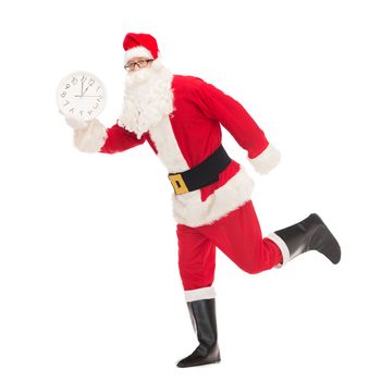 christmas, holidays and people concept - man in costume of santa claus running with clock showing twelve