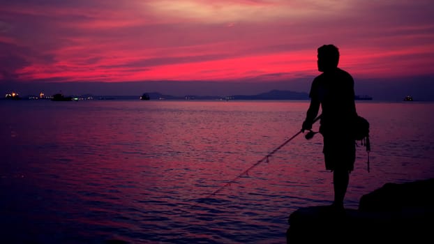 Silhouette of fishing man beside the sea