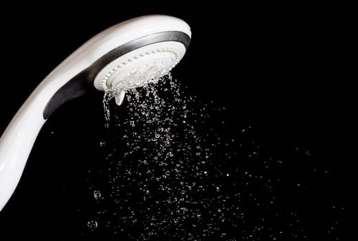 Modern shower head  with running water  isolated on black background