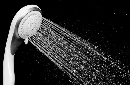 Modern shower head with running water isolated on black background