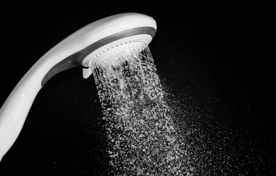 Modern shower head  with running water  isolated on black background