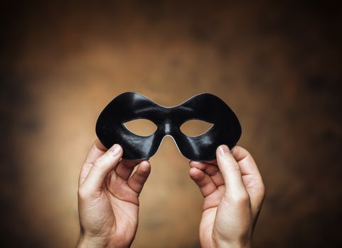 Man holding a black eye mask in his hands.