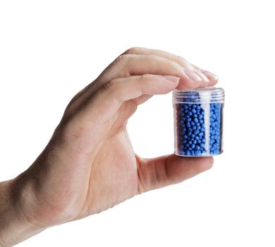 Man holding a small container with blue plastic granules, used for manufacturing.