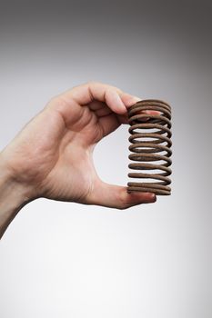 Man holding an old rusty spring is his hand.