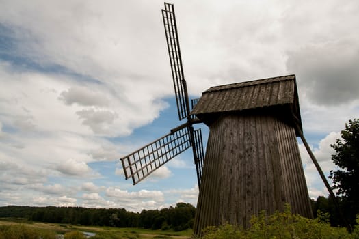 old windmill in a field near the river in the summer