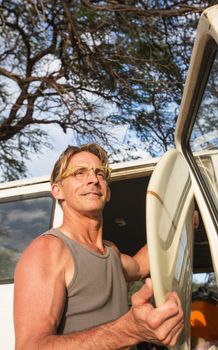 Athletic middle aged man with smile and surfboard