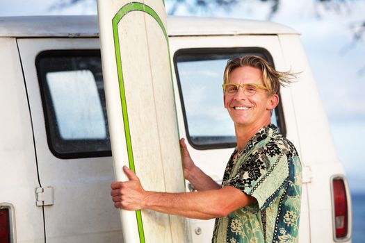 Handsome man with surfboard and wind blowing his hair