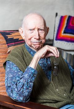 Stern elder gentleman sitting on chair in livingroom