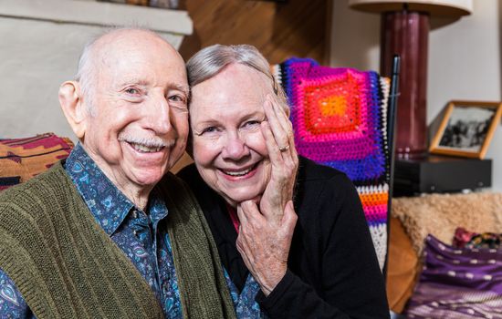 Smiling couple sitting together in living-room touching hands