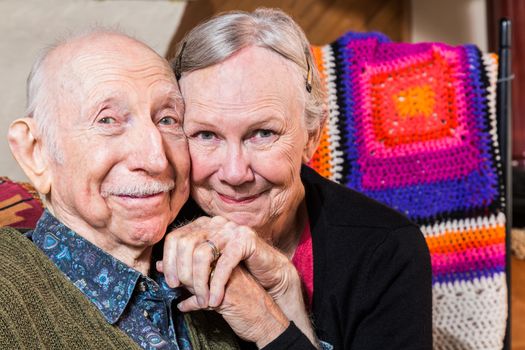 Happy elderly couple sitting in living-room with faces together