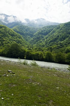 Mountains are covered with snow and the wood and surrounded with clouds