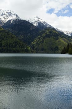 Mountains are covered with snow and the wood and surrounded with clouds