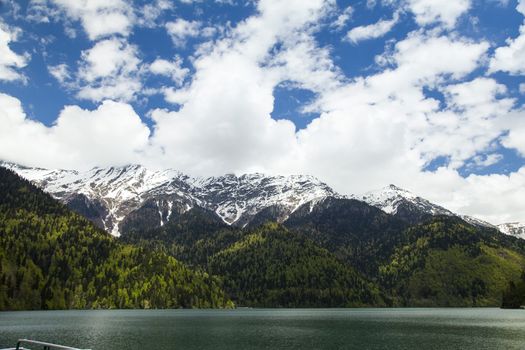 Mountains are covered with snow and the wood and surrounded with clouds