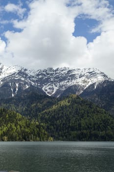 Mountains are covered with snow and the wood and surrounded with clouds