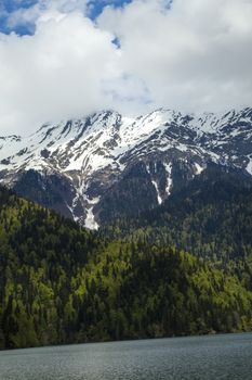 Mountains are covered with snow and the wood and surrounded with clouds