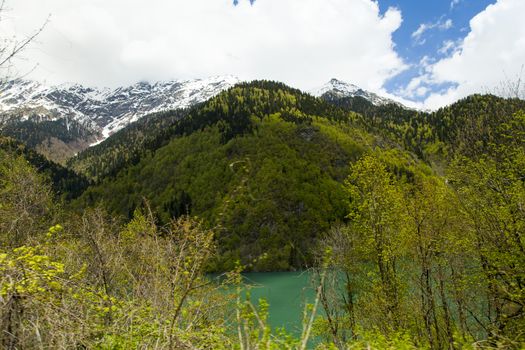 Mountains are covered with snow and the wood and surrounded with clouds