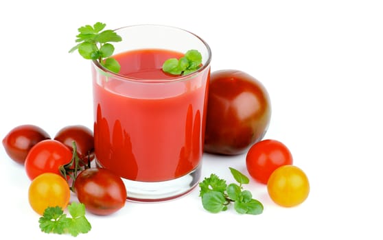 Glass of Tomato Juice and Heap of Brown, Yellow and Red Tomatoes with Greens closeup on White background