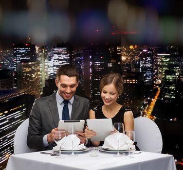 restaurant, couple, technology and holiday concept - smiling couple with menus on tablet pc computers at restaurant