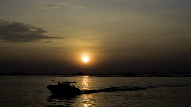 Speed boat silhouette in sea with sunset sky background