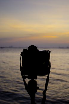 Silhouette of DSLR camera at sea with sunset sky