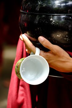 Close up of buddhist monk hands holding a vintage bowl and cup
