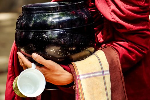 Detail of buddhist monk hands holding a bowl and cup