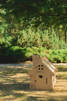 Toy house made of corrugated cardboard in the city park on the grass. The concept of eco-estate