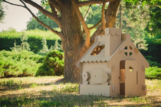 Toy house made of corrugated cardboard in the city park on the grass. The concept of eco-estate