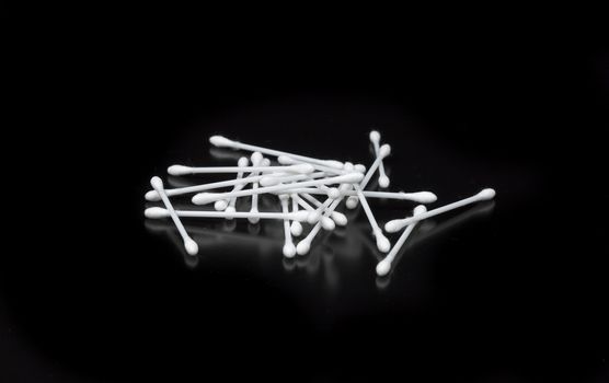 Cotton Swabs on Black Background lying on top pf each other.