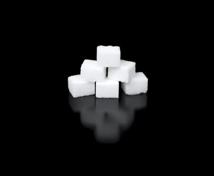 Sugar Cubes in a Pyramid with completely black background and reflection.