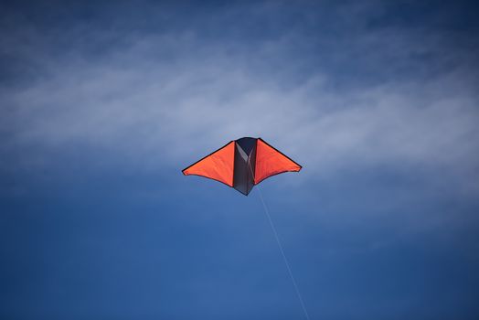 A bright colored kite flying high against a blue sky