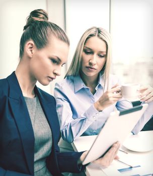 business, technology and office concept - serious businesswomen with tablet pc computers having discussion in office