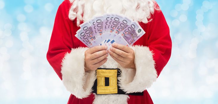 christmas, holidays, winning, currency and people concept - close up of santa claus with euro money over blue lights background