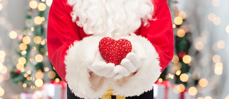 christmas, holidays, love, charity and people concept - close up of santa claus with heart shape decoration over tree lights background