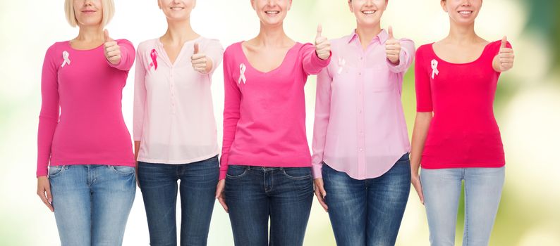 healthcare, people, gesture and medicine concept - close up of smiling women in blank shirts with pink breast cancer awareness ribbons over green background