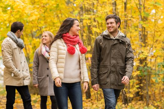 love, relationship, season, friendship and people concept - group of smiling men and women walking in autumn park