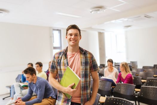 education, high school, teamwork and people concept - group of smiling students with notepads sitting in lecture hall