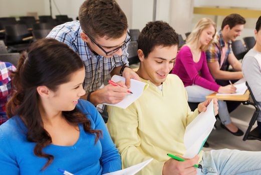 education, high school, teamwork and people concept - group of smiling students with notepads sitting in lecture hall