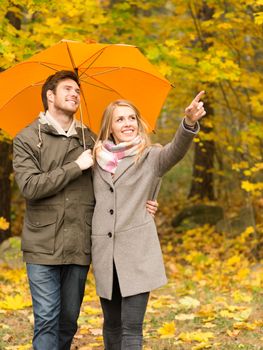 love, relationship, season, family and people concept - smiling couple with umbrella walking in autumn park