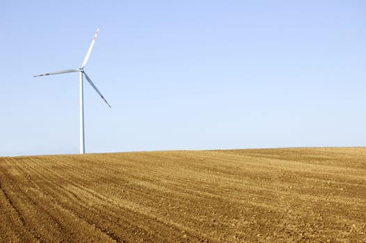 Windmill conceptual image. Windmill on the plowed field.