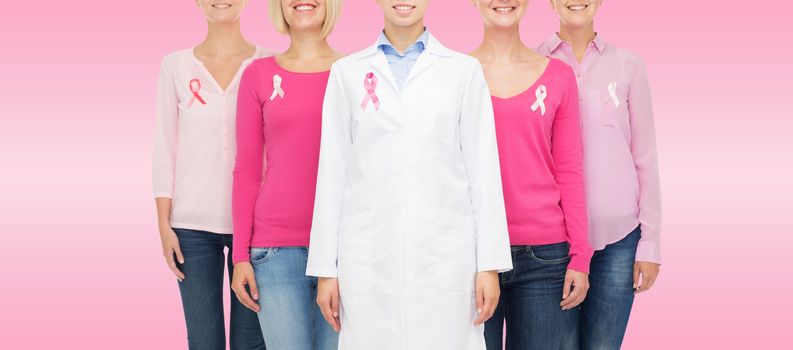 healthcare, people and medicine concept - close up of smiling women in blank shirts with pink breast cancer awareness ribbons over pink background