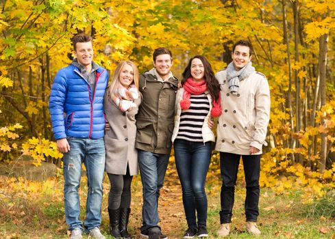 love, relationship, season, friendship and people concept - group of smiling men and women hugging in autumn park