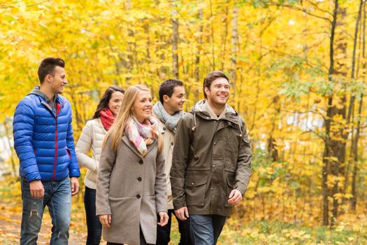 love, relationship, season, friendship and people concept - group of smiling men and women walking in autumn park