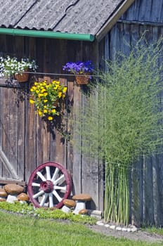 wall decorations in summer farm - flowers, stone and carriage wheel