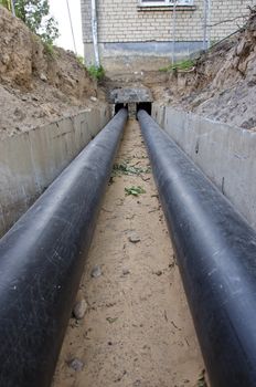 new plastic modern technology black heating pipes in trench near city house