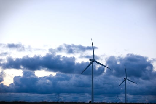 Windmill conceptual image. Windmills against cloudy sky.