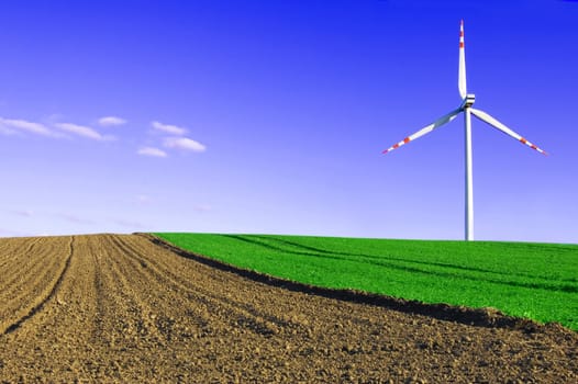 Windmill conceptual image. Windmill on the green and plowed field.