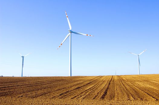 Windmill conceptual image. Windmills on the plowed field.